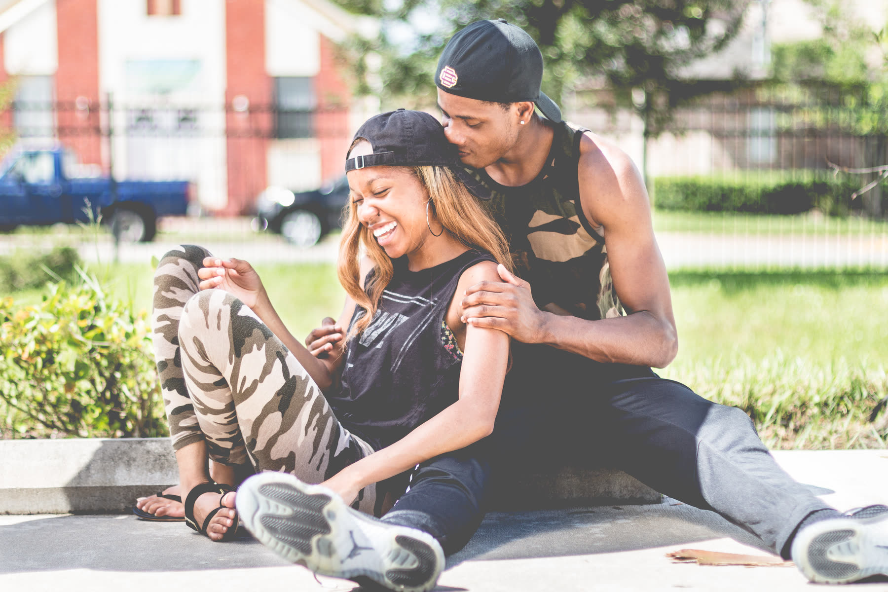 Couple complice qui rit ensemble, assis dehors